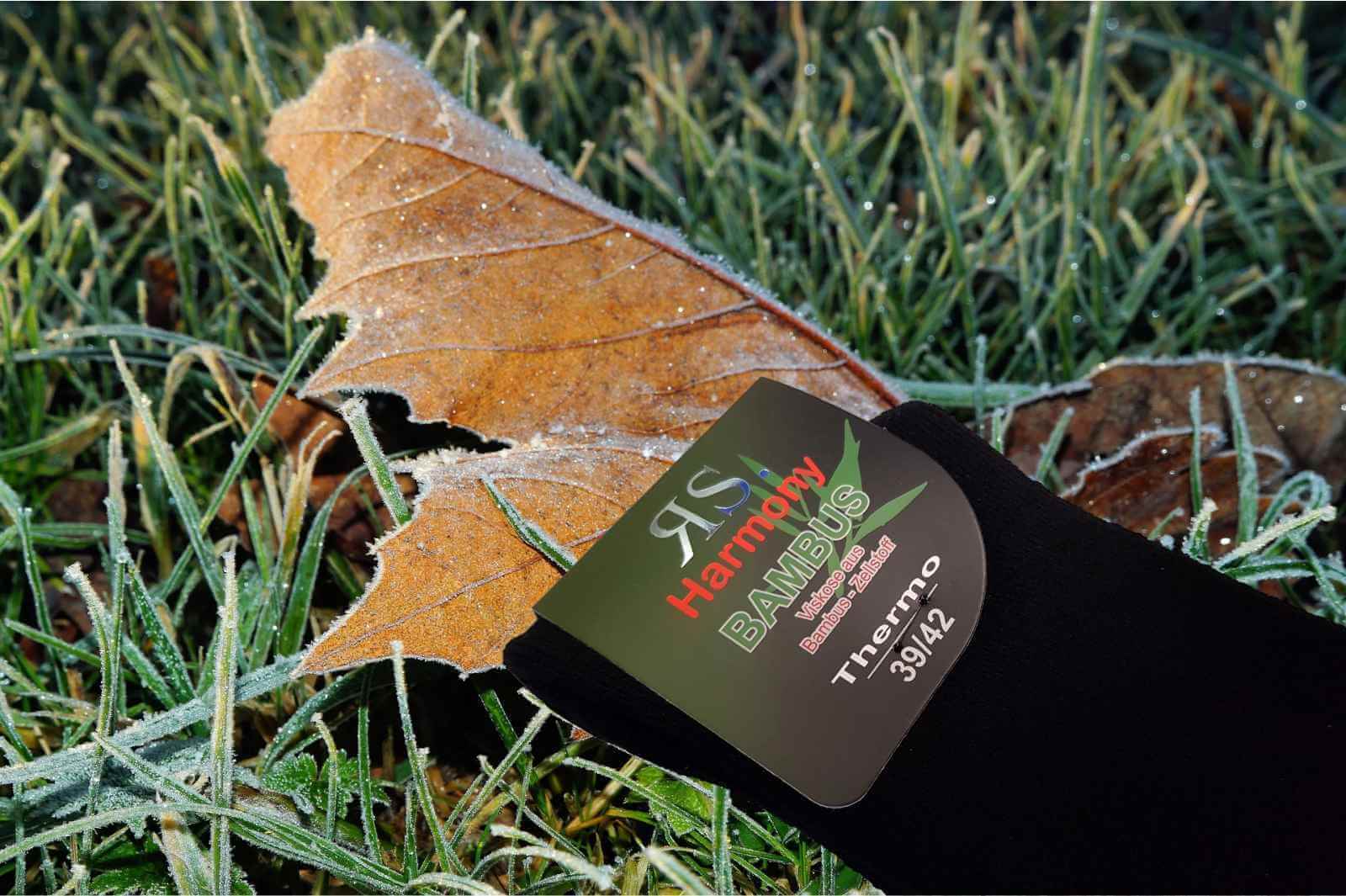 Chaussettes bouclettes noires posées sur de l'herbe gelée pour garder les pieds au chaud cet hiver.