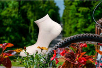 Chaussettes courtes blanches à vélo dans un cadre ensoleillé avec des fleurs colorées.