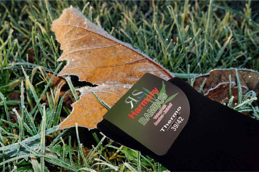 Chaussettes bouclettes noires posées sur de l'herbe gelée pour garder les pieds au chaud cet hiver.