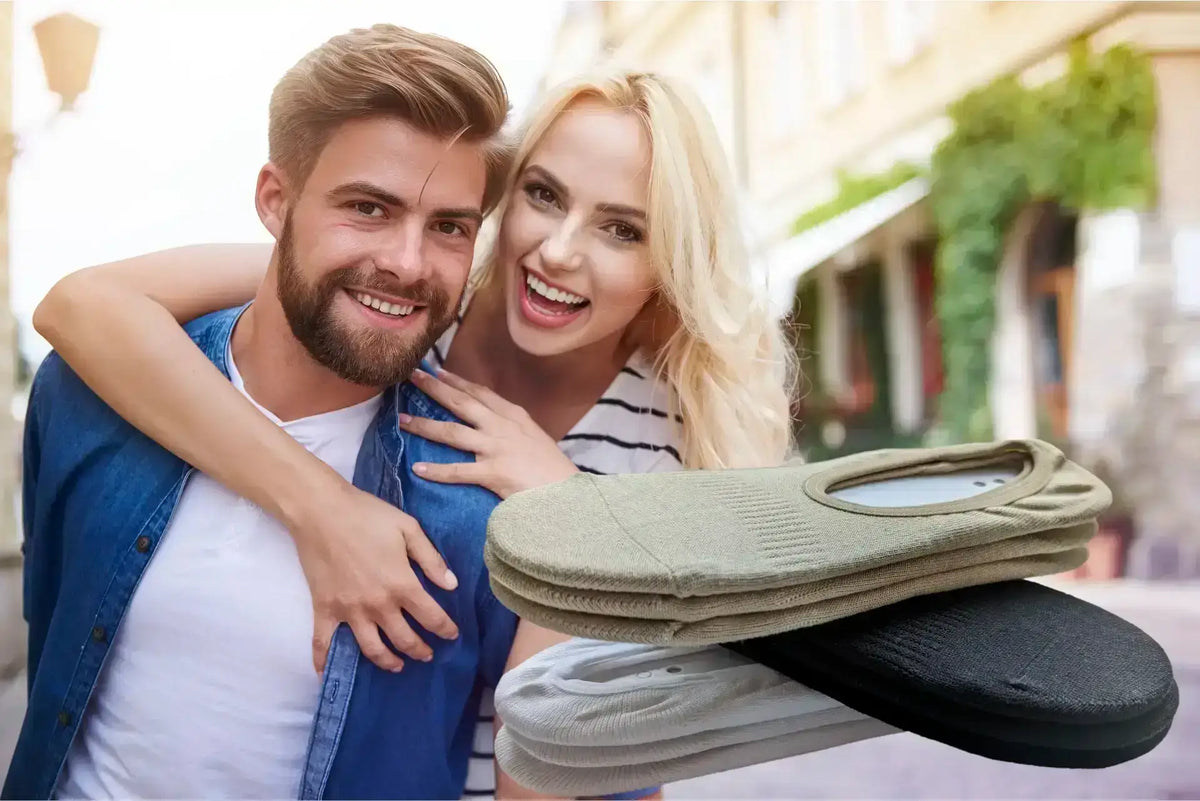 Chaussettes invisibles homme présentées avec un couple souriant dans une rue ensoleillée.