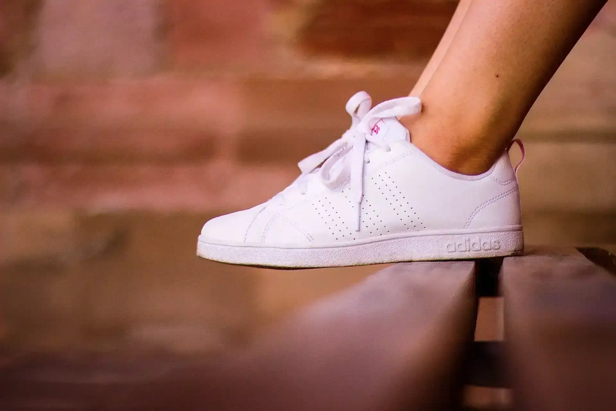 Chaussettes dans les baskets avec des chaussures blanches sur un banc en bois