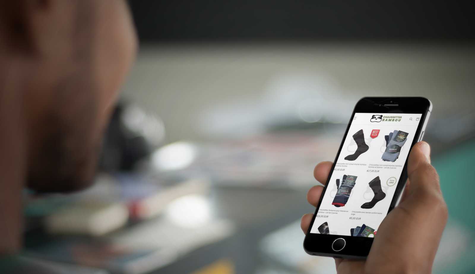 Un jeune homme navigue sur son smartphone pour découvrir le site internet chaussettes-bambou.fr afin d'acheter ses chaussettes en viscose de bambou.
