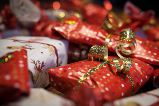 Cadeaux de Noël au pied du sapin avec leurs emballages festifs rouges et leurs rubans dorés
