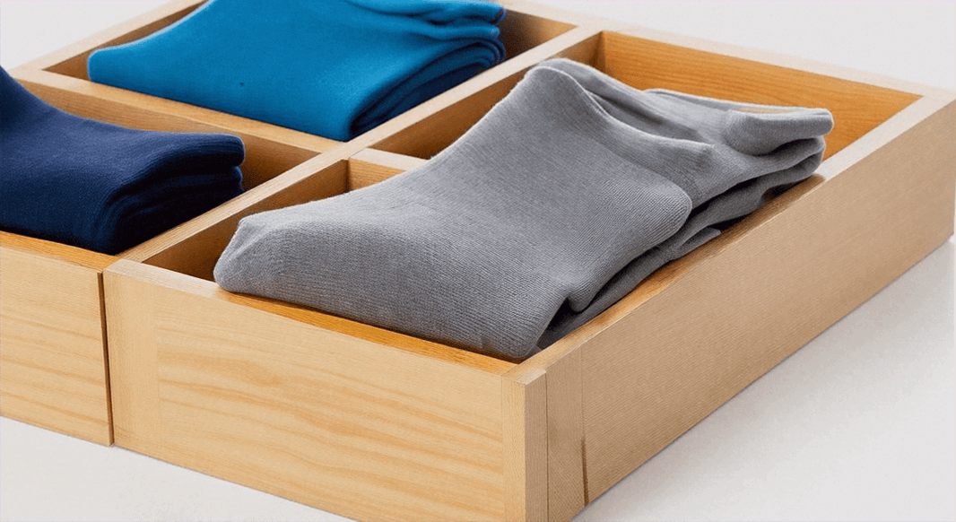 Chaussettes indispensables pour la rentrée présentées dans un tiroir en bois organisé.