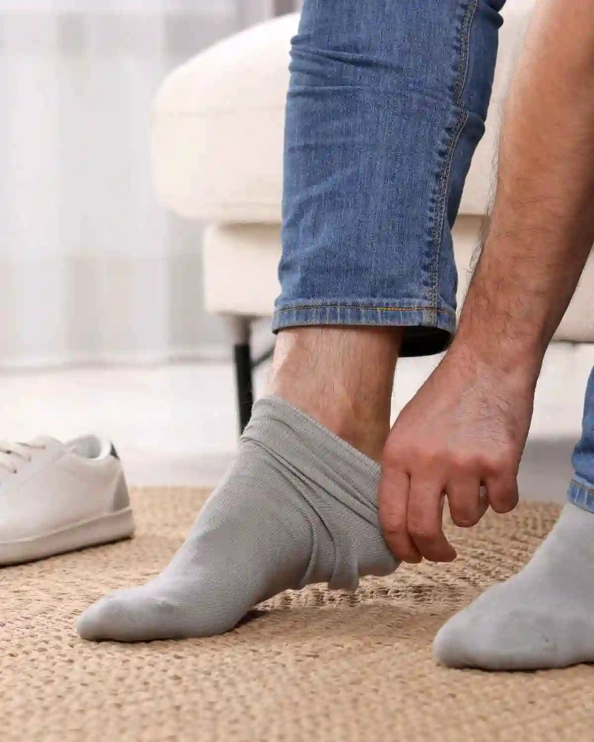 Homme en train d'enfiler des chaussettes bambou homme grises confortables sur un tapis.