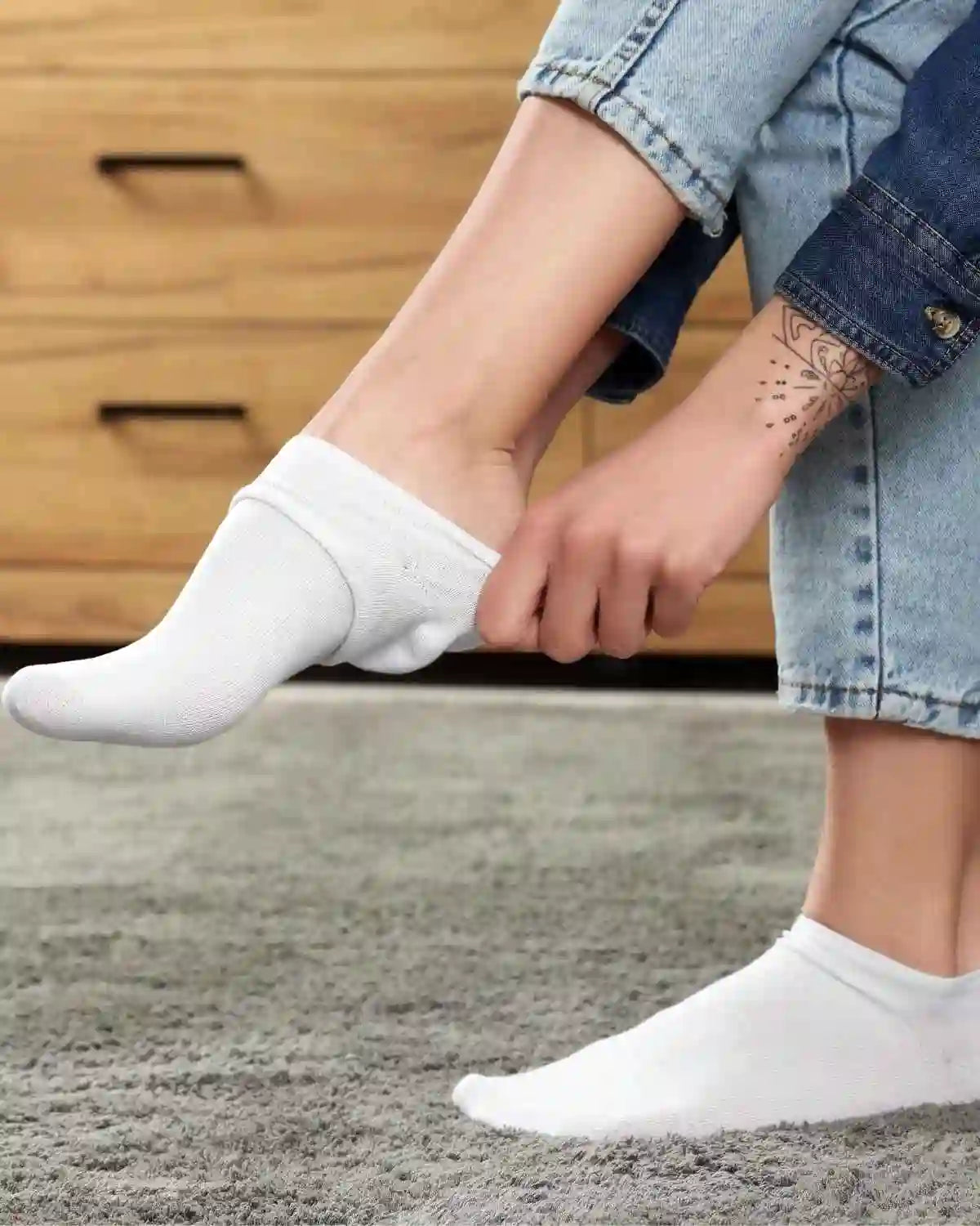 Chaussettes bambou femme blanches, confortables et élégantes, en train d'être enfilées sur des pieds nus.